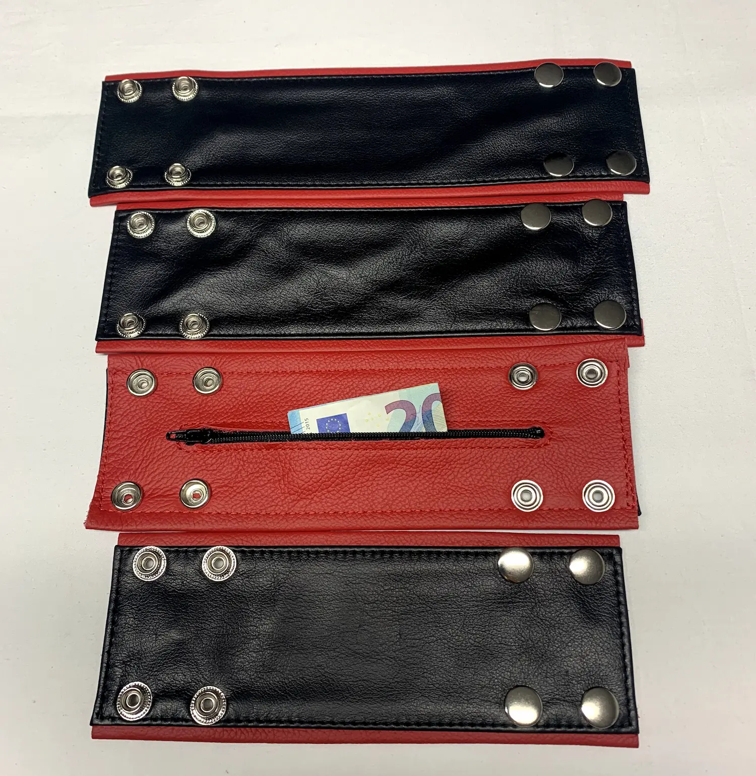 Aussen schwarz Innen rotes Armband aus Echtleder aufgeteilt in alle größen untereinander mit Geldschein im Reisverschluss