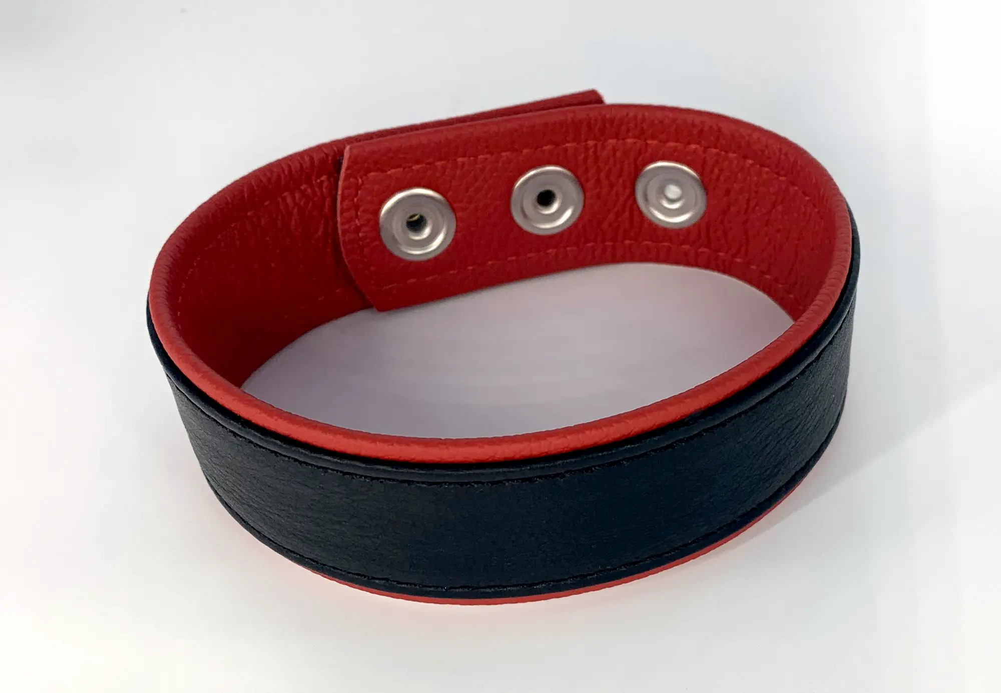 Schwarzes Leder-Oberarmband mit roter Innenseite, geschlossen, Druckknopfverschluss sichtbar